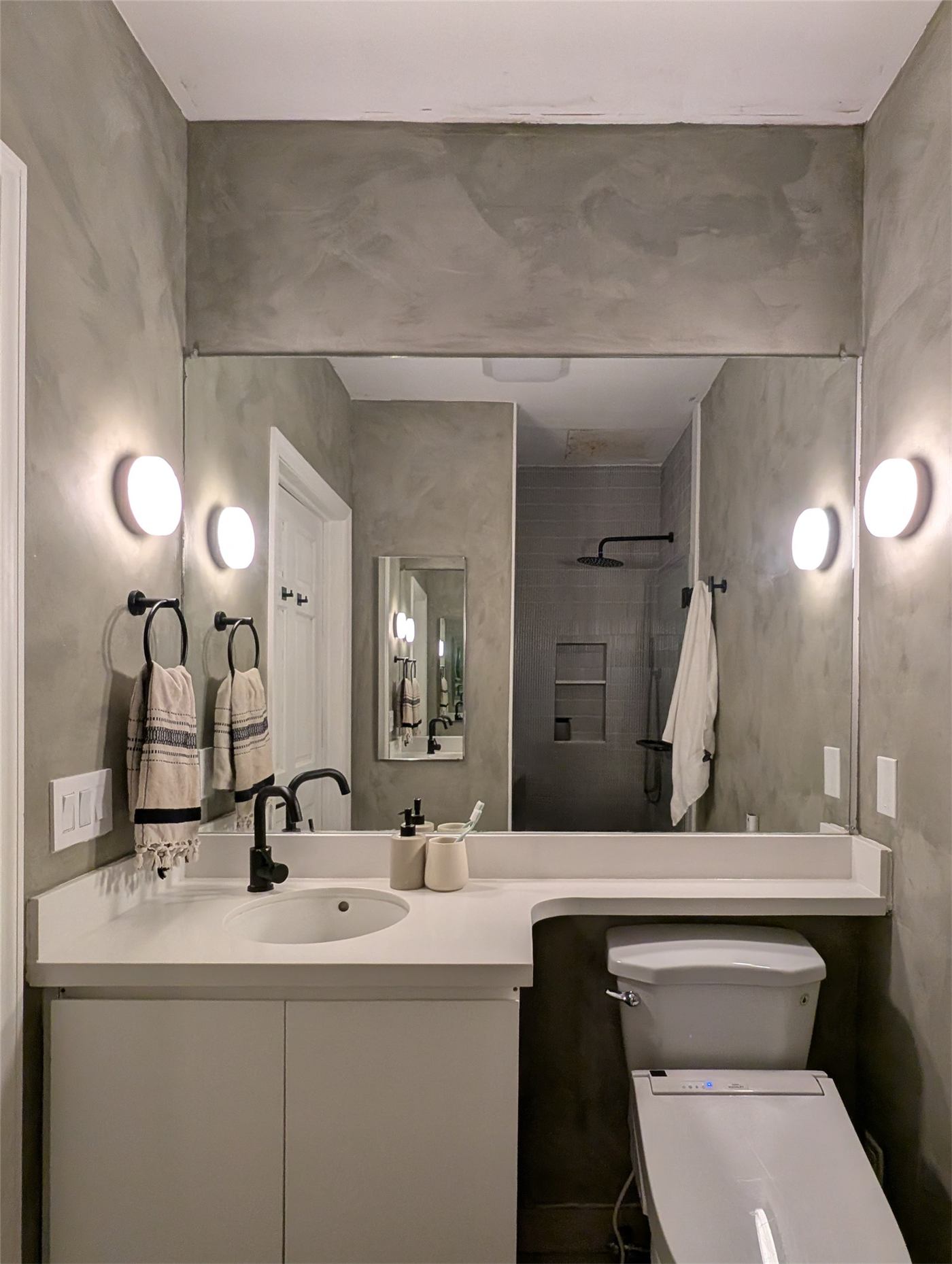 Bathroom No. 2 — full-width mirror reflecting light through the calm green room
